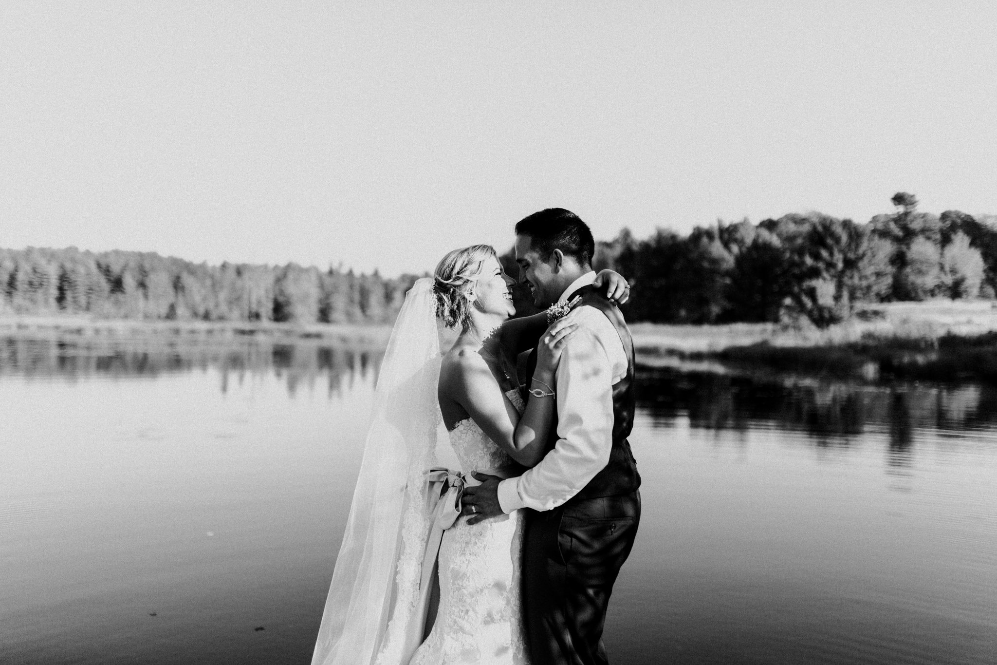 bride and groom standing on a dock looking at each other