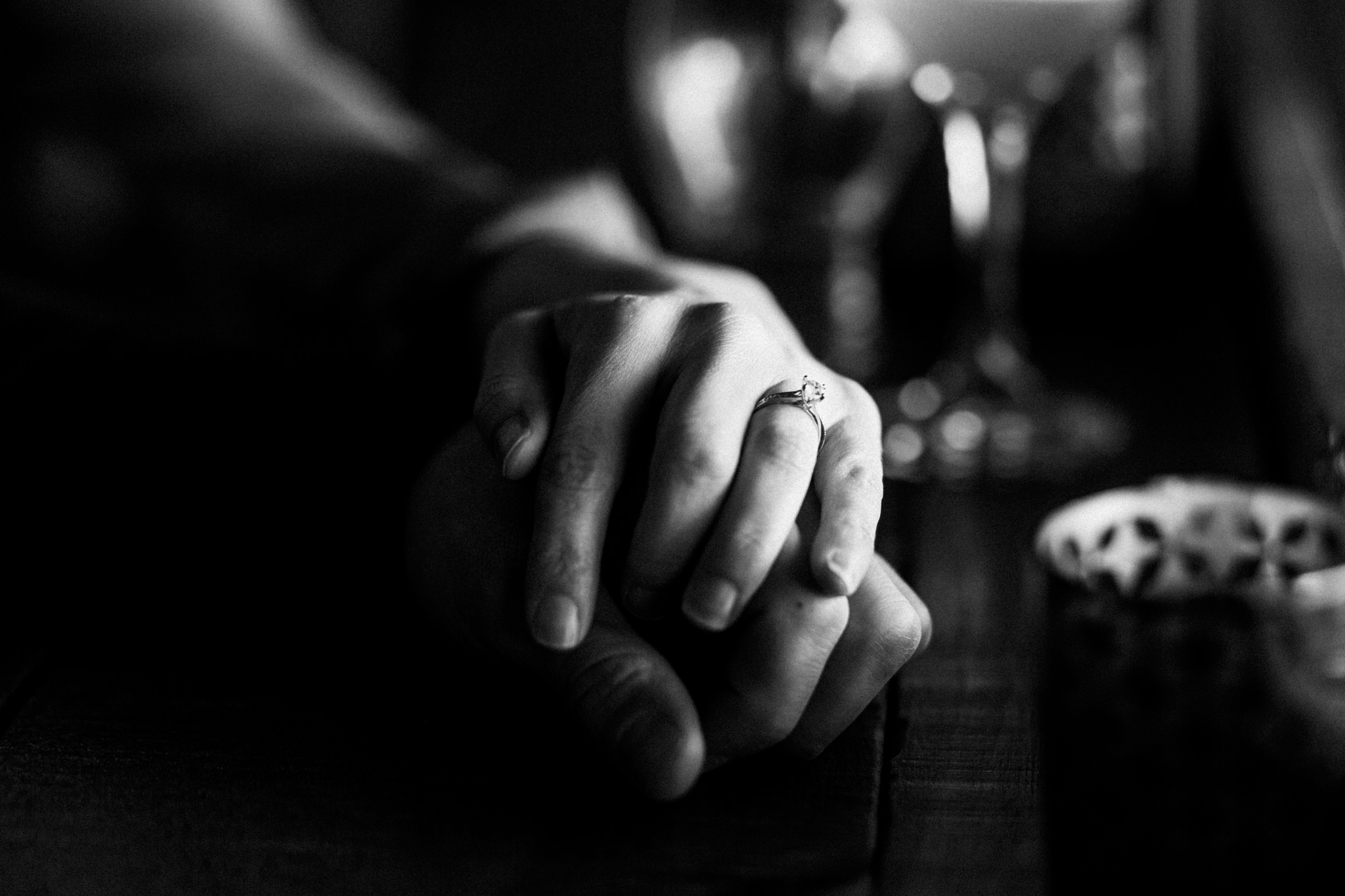 couple holding hands with engagement ring showing
