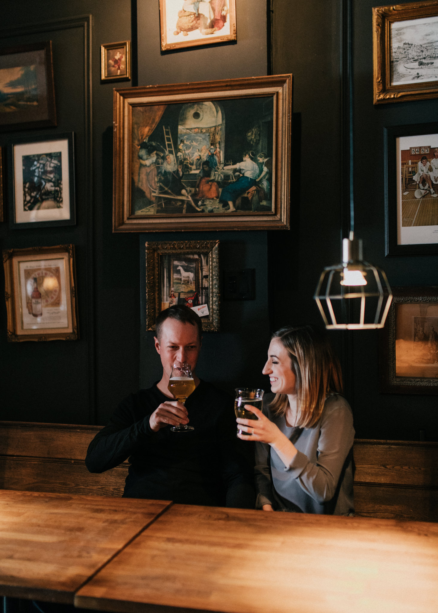 couple smiling and drinking beer in a cozy pub in leslieville, toronto