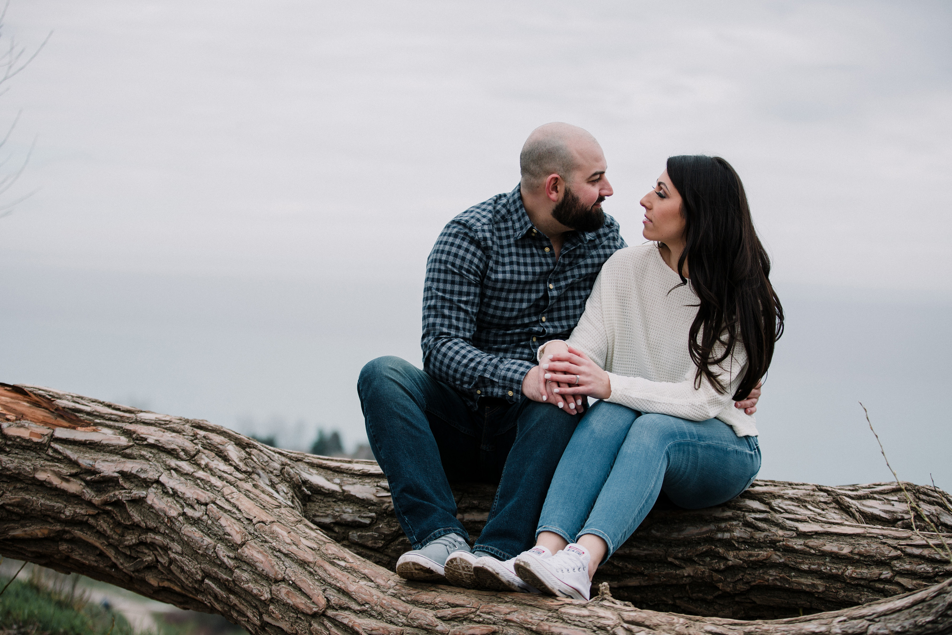 engaged couple sitting together on a log during a spring engagement shoot