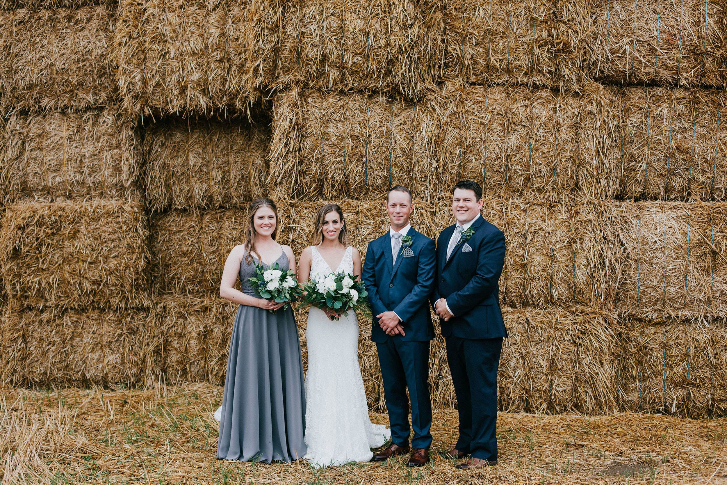 bridal party standing infront of haystack