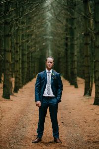 groom standing in wooded area
