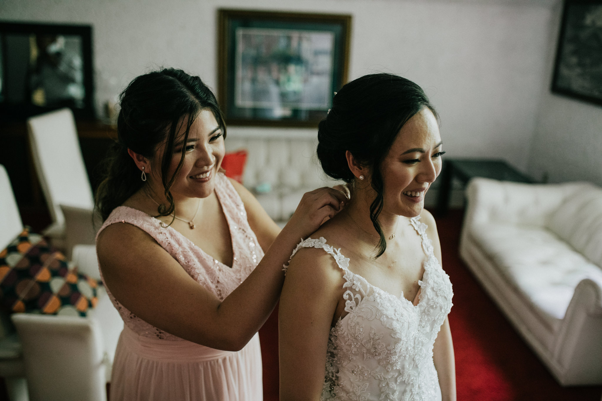bridesmaid putting a necklace on a bride